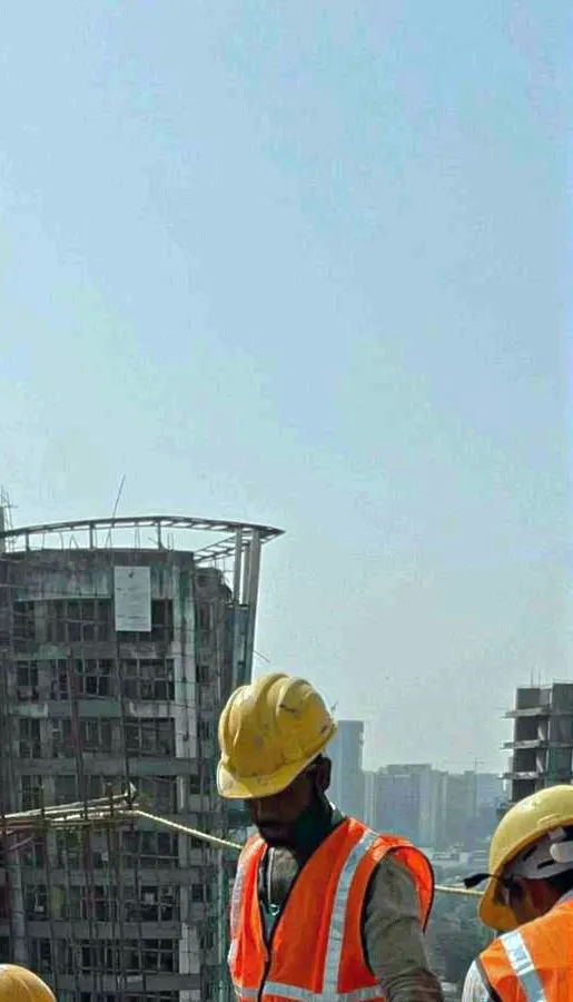Construction workers in hard hats and safety vests beside a building under construction