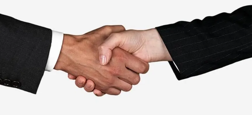 Two people in suits shaking hands on a deal