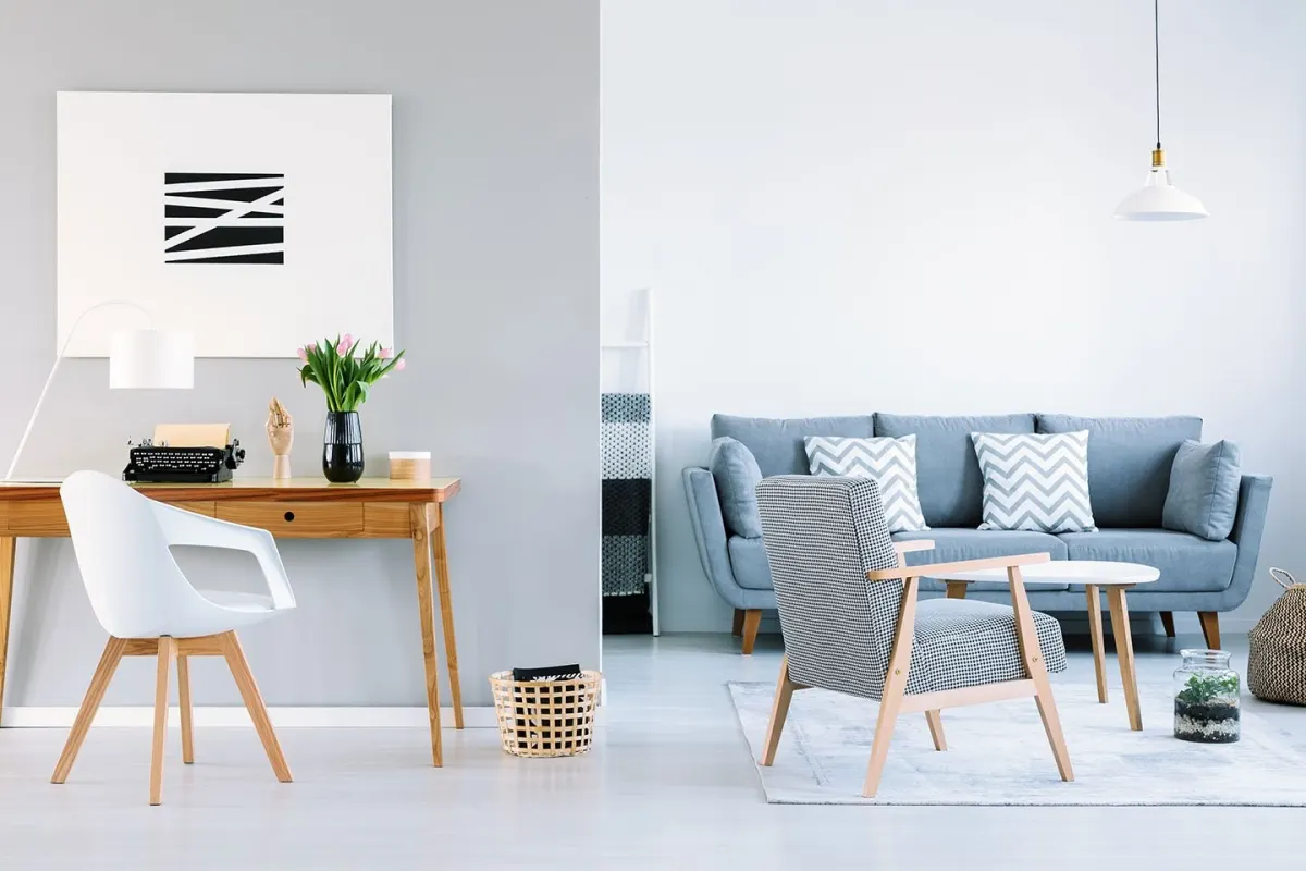 A bright, modern living room with a grey sofa, armchair and desk